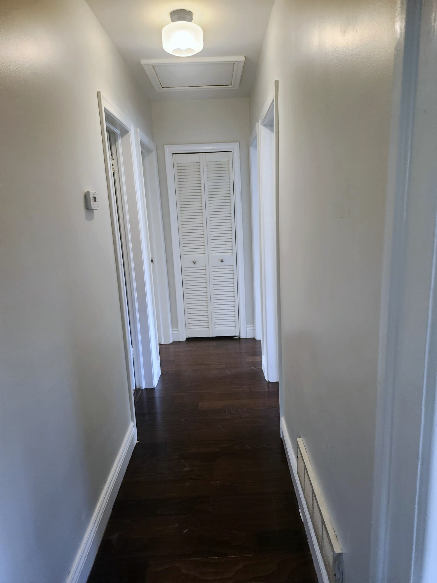 Clean hallway with white doors and dark hardwood floors