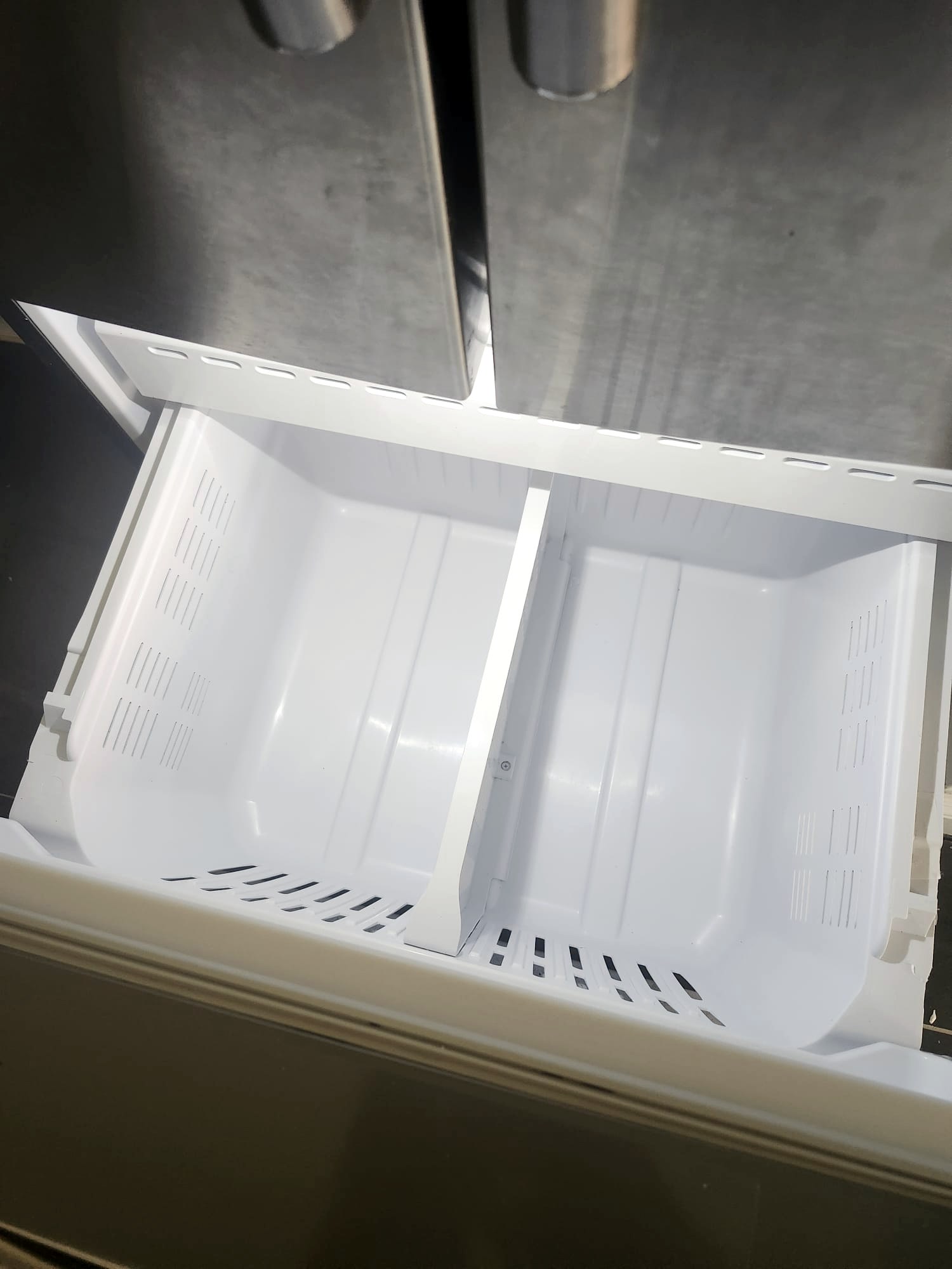 Clean freezer drawer inside a stainless steel fridge